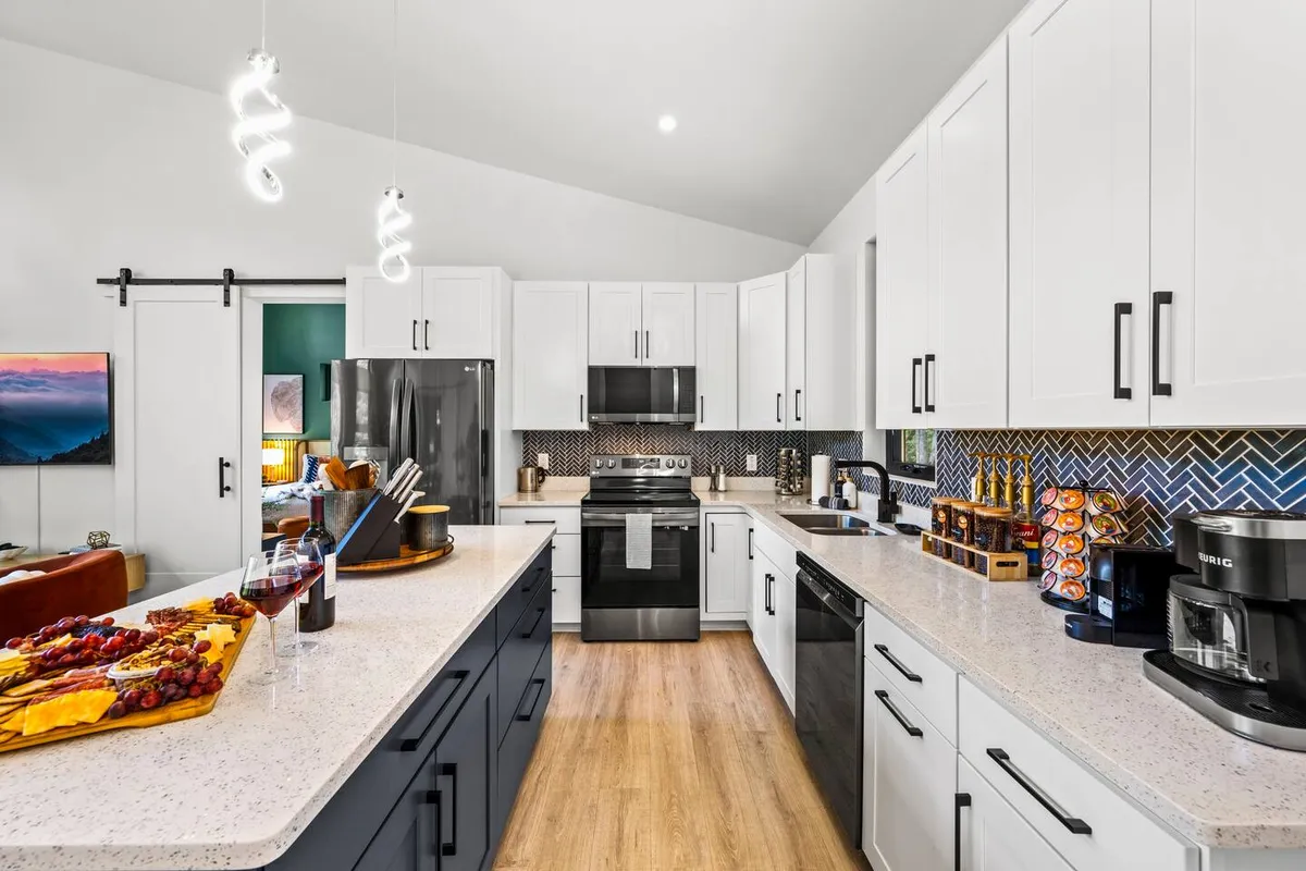This image showcases a spacious kitchen island adorned with a charcuterie board, surrounded by stainless steel appliances and a vibrant backsplash. The scene is clearly set for both cooking and entertaining, emphasizing the kitchen’s role as a social and culinary hub.