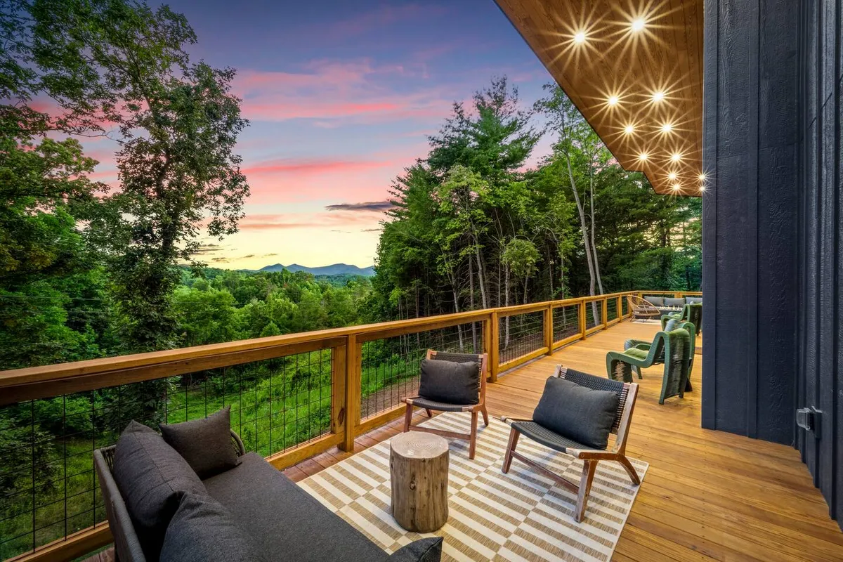 This image presents an inviting outdoor seating area set against a vibrant sunset sky, surrounded by natural mountain landscape. The scene conveys tranquility and the potential for both relaxation and socializing, with comfortable seating that invites productivity or unwinding after a day’s work.